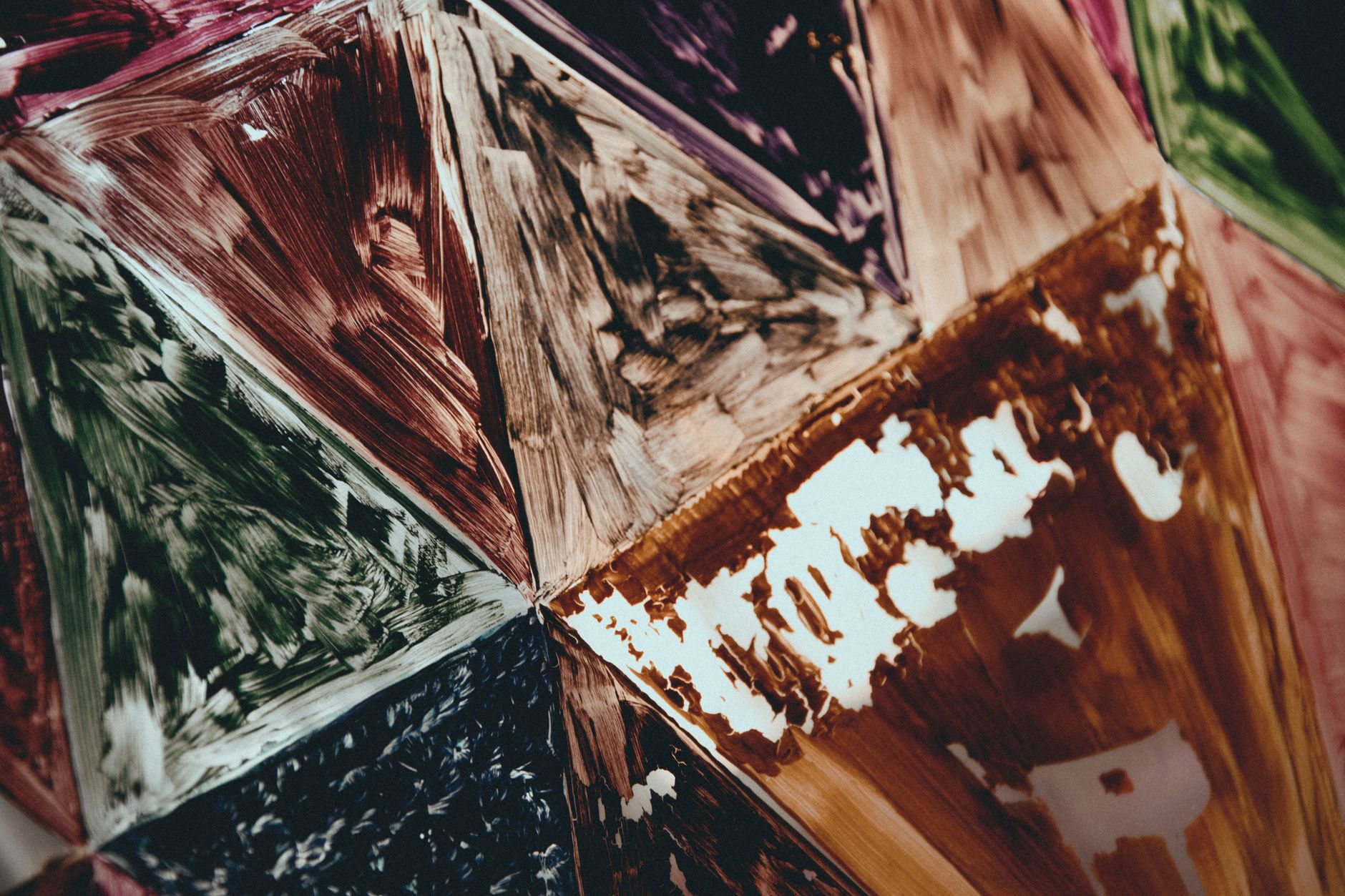 Extreme detail crop where a painted brushstroke edge meets a leaded glass seam — metal, solder line, pigment ridge